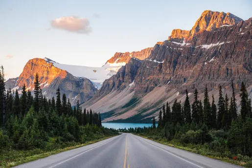 Wide shot of forest road, Large mountain range and river in distance.