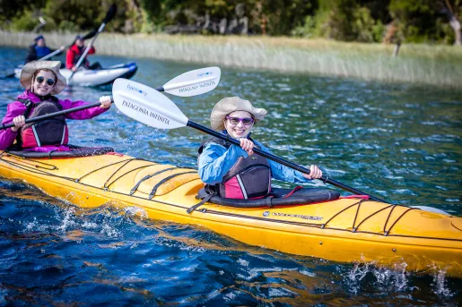 Four guests in kayaks, smiling at camera.