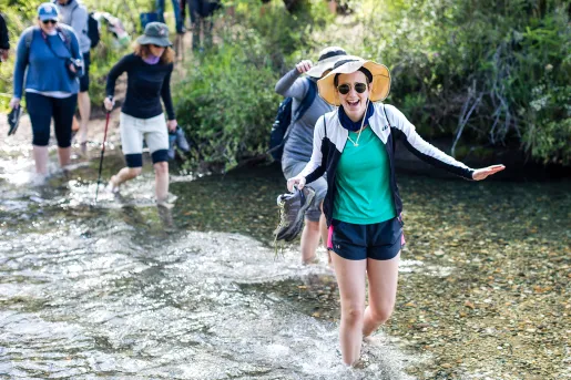 Four guests trekking through small river.