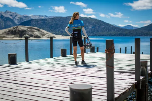 Guest in bike gear on pier, overlooking mountains, lake.