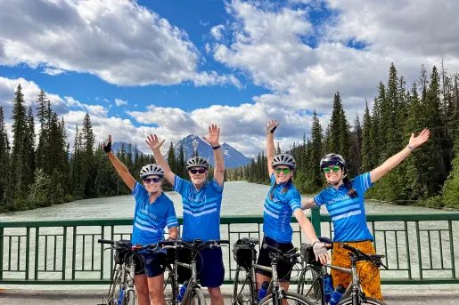 Four guests with arms outstretched, gesturing to trees, mountains.