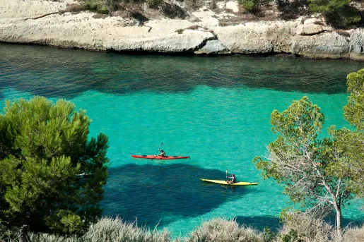 Wide shot of two guests kayaking through blue water.