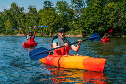 three guests kayaking, one is celebrating in background.