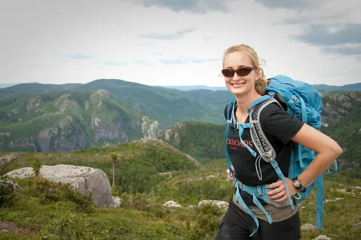 Guest smiling for camera, forested alpine mountain range in background.