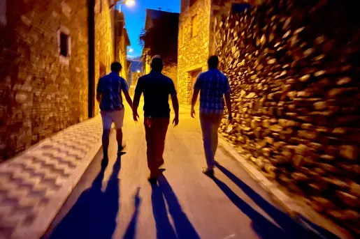 Three people walking down a charming alley at night