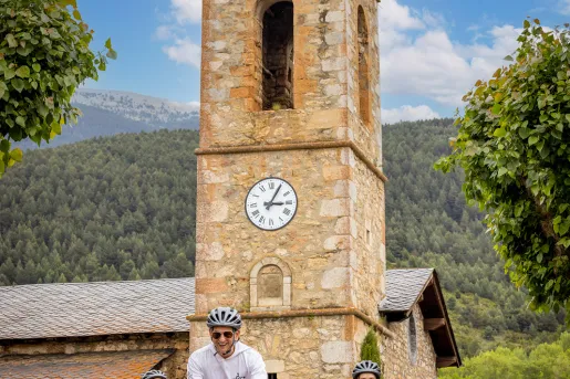 Three people biking past an old stone church