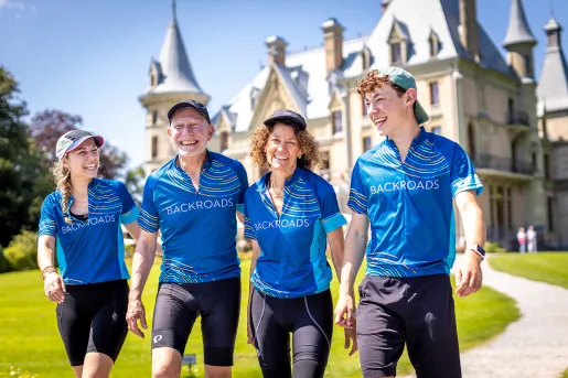 Four guests walking away from castle-like building. All smiling.