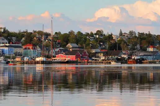 Wide shot of seaside town at sunset, vibrant red houses scattered throughout.