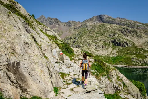 Guest hiking along rocky cliffside, river to her right.