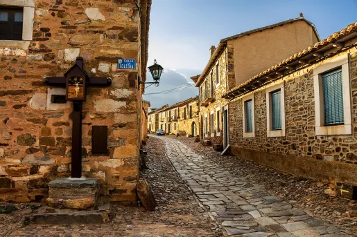 Alleyway shot of stone-built town, windows, doors dot the alley.