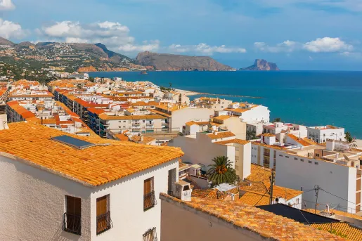 Shot of coastal town, white and tan houses, ocean.