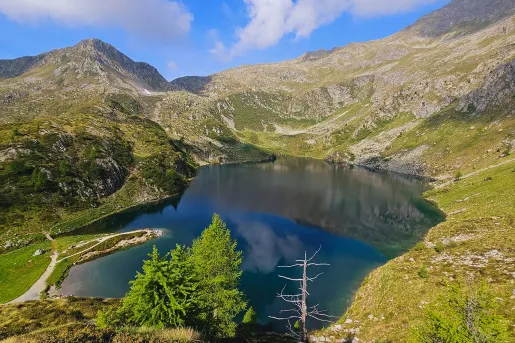 Wide shot of blue lake, ring of mountains all around.