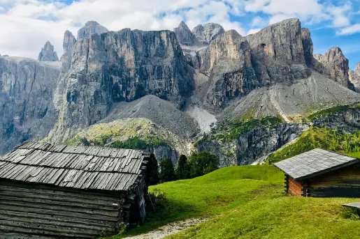 Shot of two old, wooden houses, angular cliffs in distance.