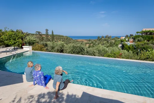 Three women resting by a hotel pool in Greece.