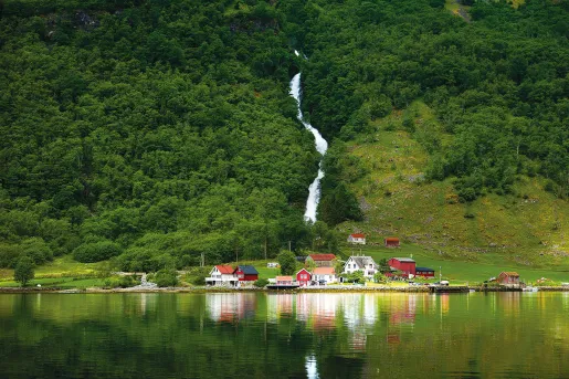 Waterfall cascading down a green grassy hill in Norway