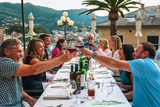 Group of guests at dinner, cheersing wine glasses.