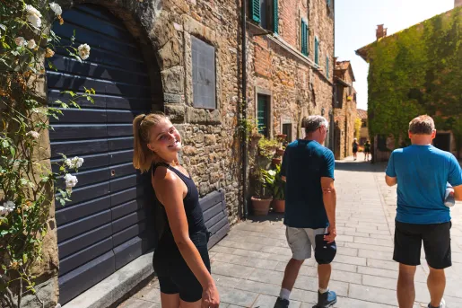 Three guests walking down brick road, one smiling at camera amidst storefronts.