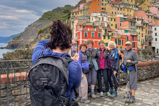 Over the shoulder shot of guest taking photo of other guests. Colorful Italian houses and coast in background.