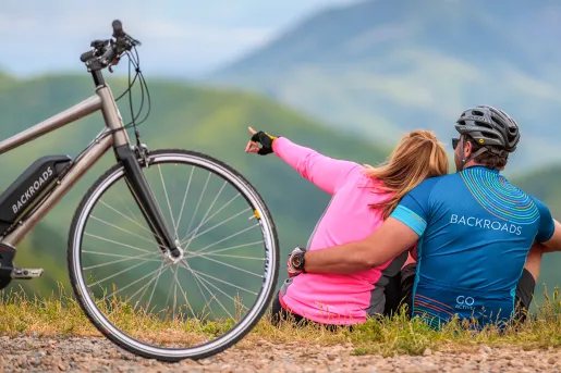 Two guests sitting, one pointing off camera, bike in foreground.