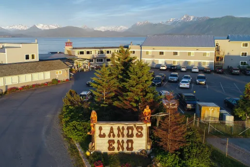 Exterior view of hotel buildings next to a large lake and tall mountains in the background