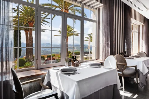 Dining table with white and gray table cloths, next to a large window