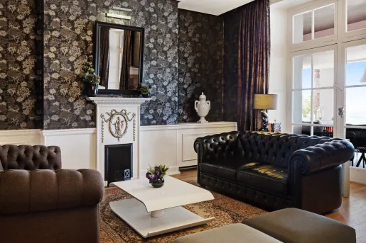 Indoor foyer, with black and brown leather couches, with a large window over a fireplace