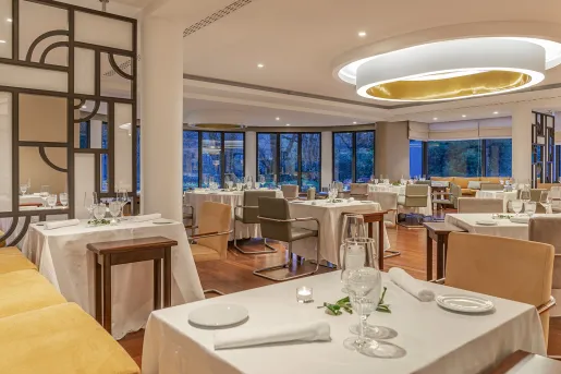 Dining hall with a large circular light in the ceiling, and wine glasses on each table