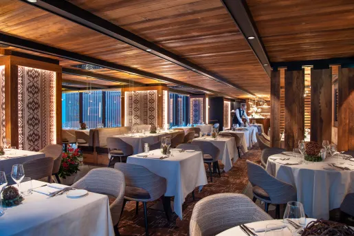 Indoor dining hall in a wooden lodge-style room, with gray cushioned chairs