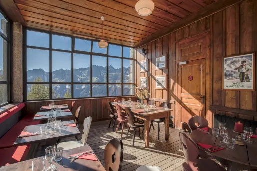 Dining area in a wooden-lodge room with large windows looking out to the mountains