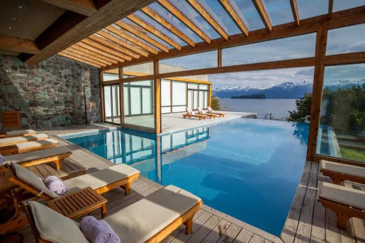 Outdoor pool with reclining chairs, looking out to snow-capped mountains in the distance