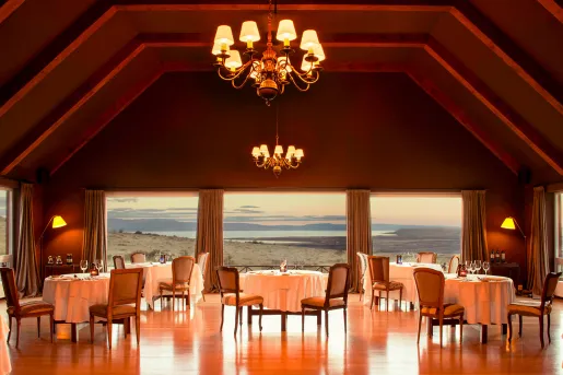 large dining room lit by chandeliers with windows overlooking ocean