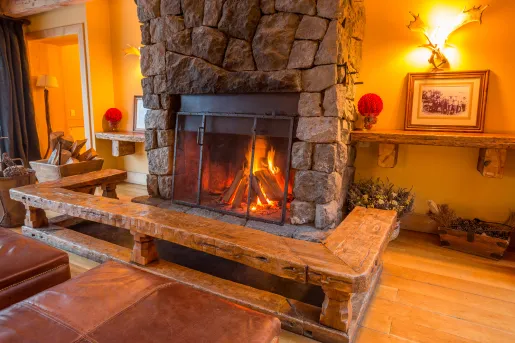 Stone fireplace with illuminated portraits on either side, with a wooden bench in front