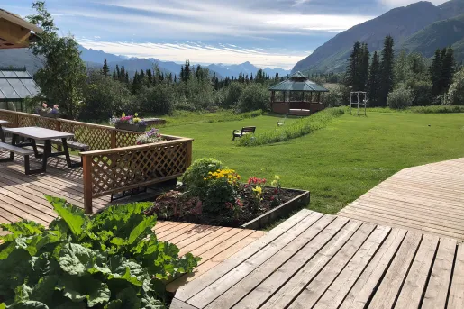 Outdoor patio with a wooden walkway and an open grass field looking out to the mountains