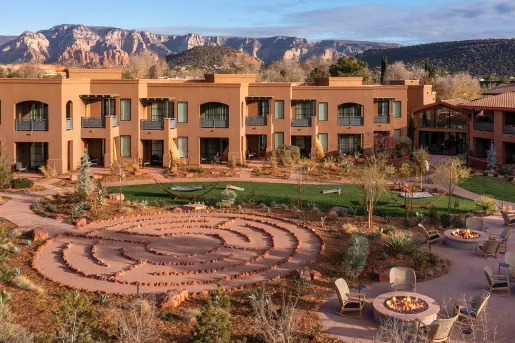 Exterior view of brown hotel building with a stone pathway in an outdoor garden