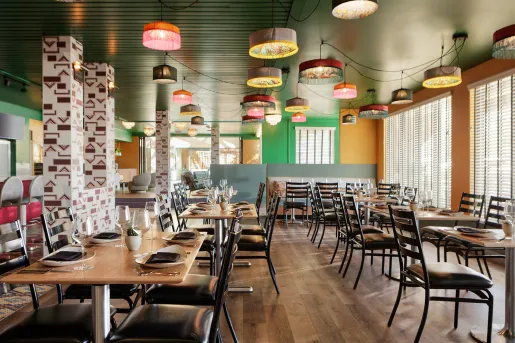 Indoor dining area with black chairs and wooden tables, with colorful light fixtures