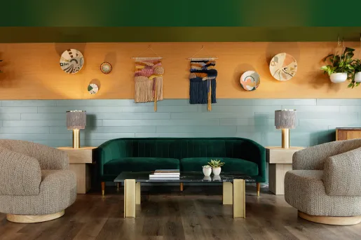 Indoor lounge with a green sofa and tan, cushioned chairs and décor on the wall