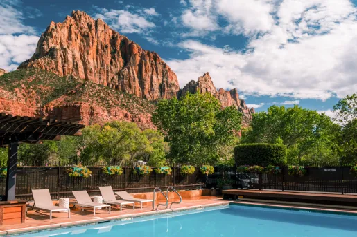 pool with lounge chairs and mountains in background