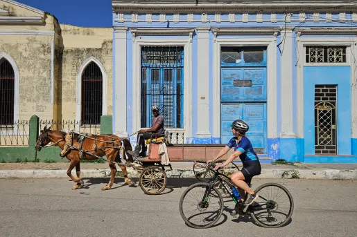 Woman riding a bike while looking at a man on a horse carriage