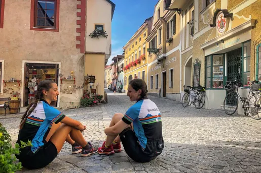 Two women sitting on the floor of a stone pathway 
