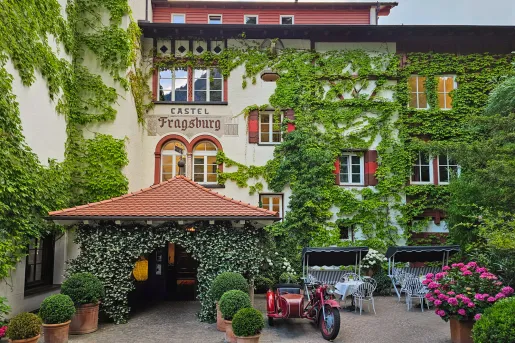 ivy covered hotel entrance with bistro tables out front