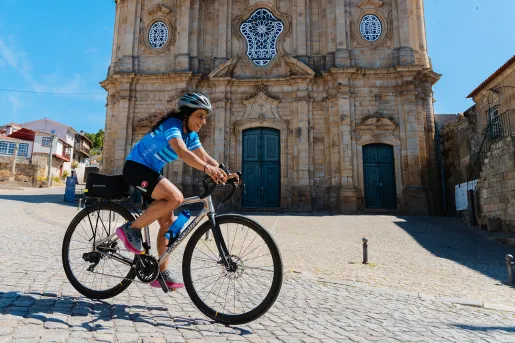 Woman biking on a stone path in a town center