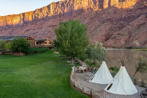 Grass field with two small, white tents next to a pond