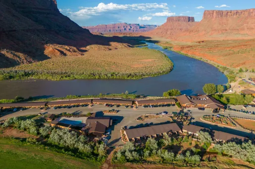 Multiple brown building next to a large canyon valley with a river in the background