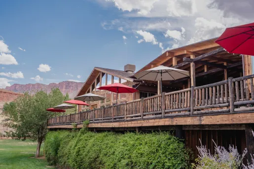 Elevated cabin-style building with wooden railings, in front of a grass valley