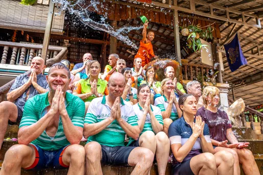 a group of people get splashed with water in a ceremony outside a temple