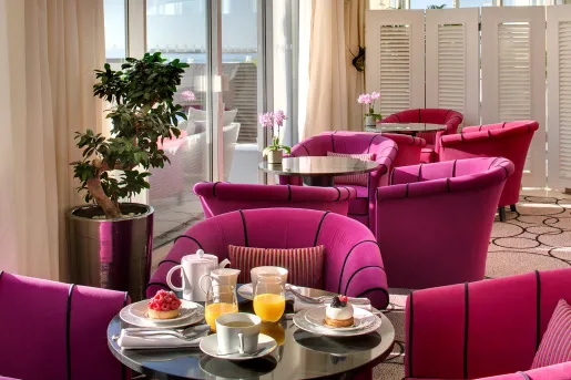 Indoor lounge with glass coffee tables and pink, cushioned chairs