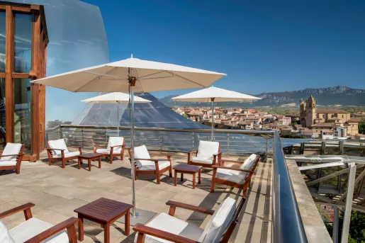 Outdoor rooftop patio with wooden chairs looking out to a small town