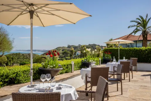 Outdoor dining patio with large umbrellas, looking out to a large valley