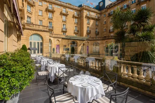Outdoor balcony with dining tables and metal chairs