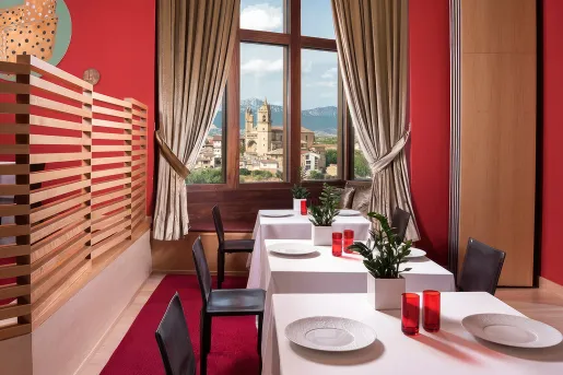 Indoor dining area with tables cover with a white cloth, and wine glasses on each table